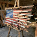 Handmade battle-worn wooden American flag on an easel in the workshop